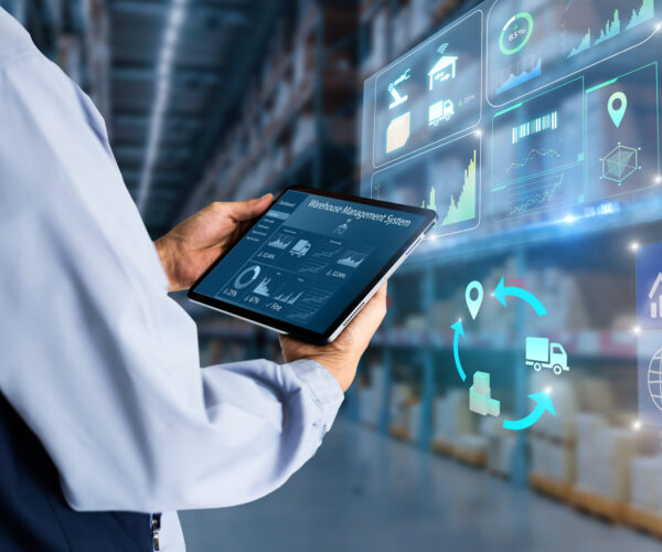 Manager using digital tablet,showing warehouse software management dashboard on blurred warehouse as background
