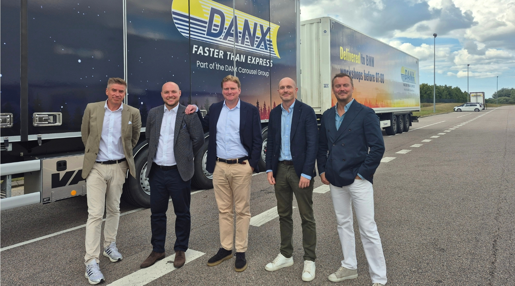 DANX and BMW Northern Europe representatives in front of branded DANX vehicles at the Staffanstorp distribution centre